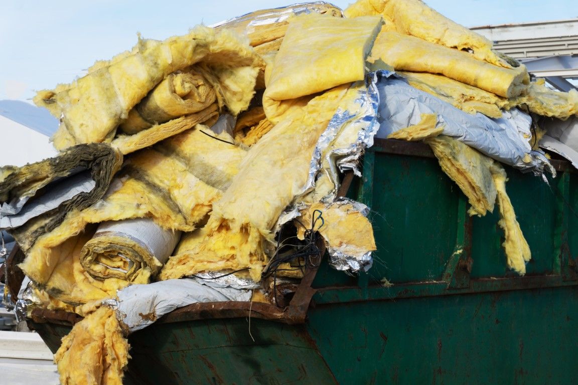 Close-up of construction debris and insulation loaded into a bin